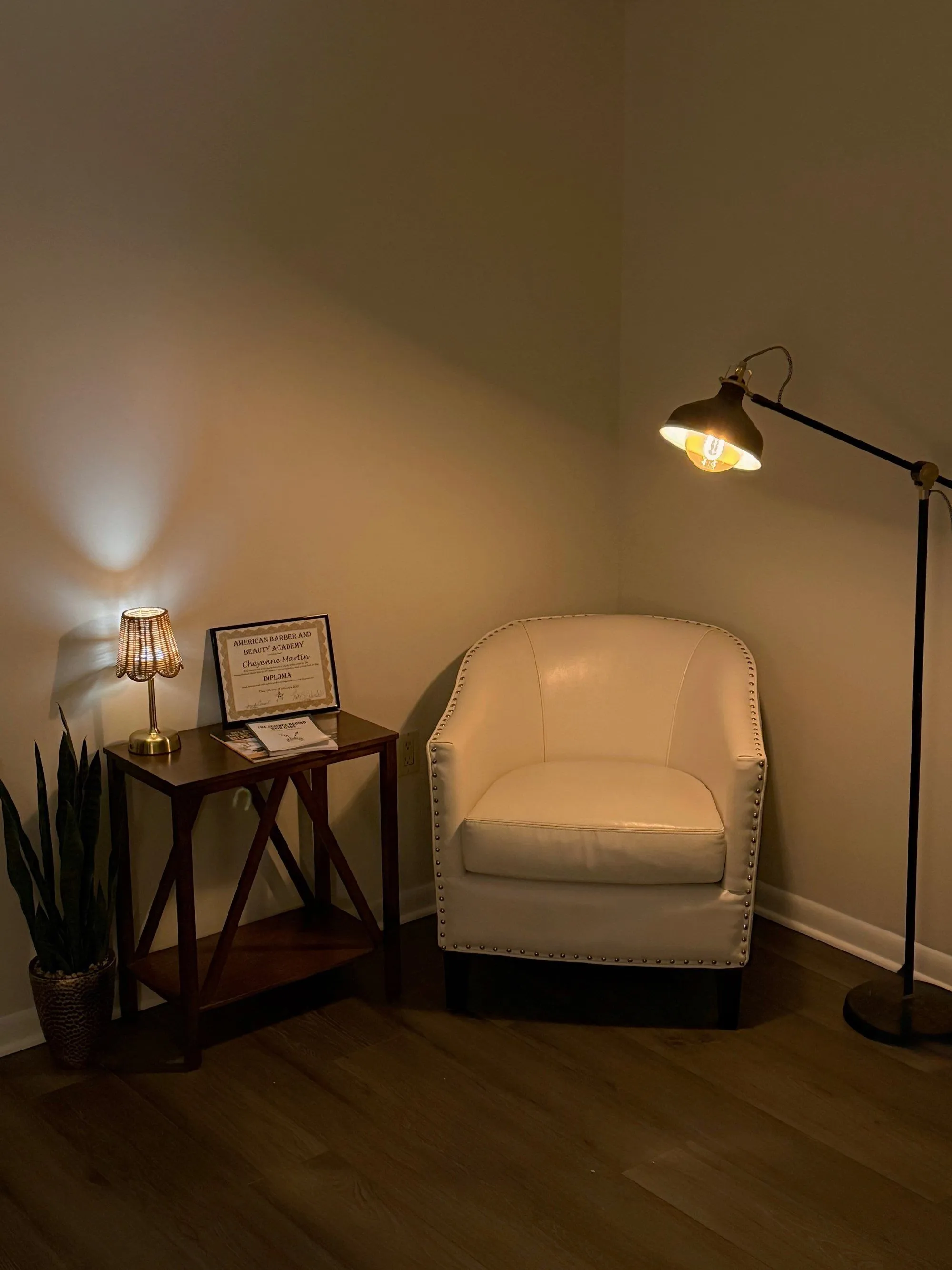 Waiting corner at Skin by Cheyenne with a cream chair, lamp, and esthetician certificate